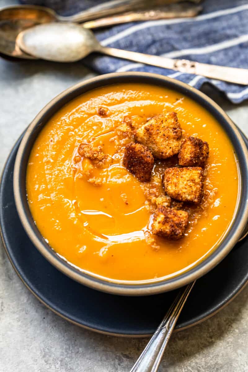 roasted butternut squash soup topped with cinnamon croutons in a black bowl