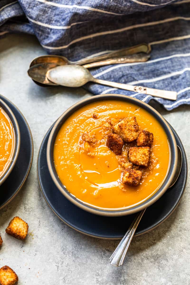 roasted butternut squash soup topped with cinnamon croutons in a black bowl