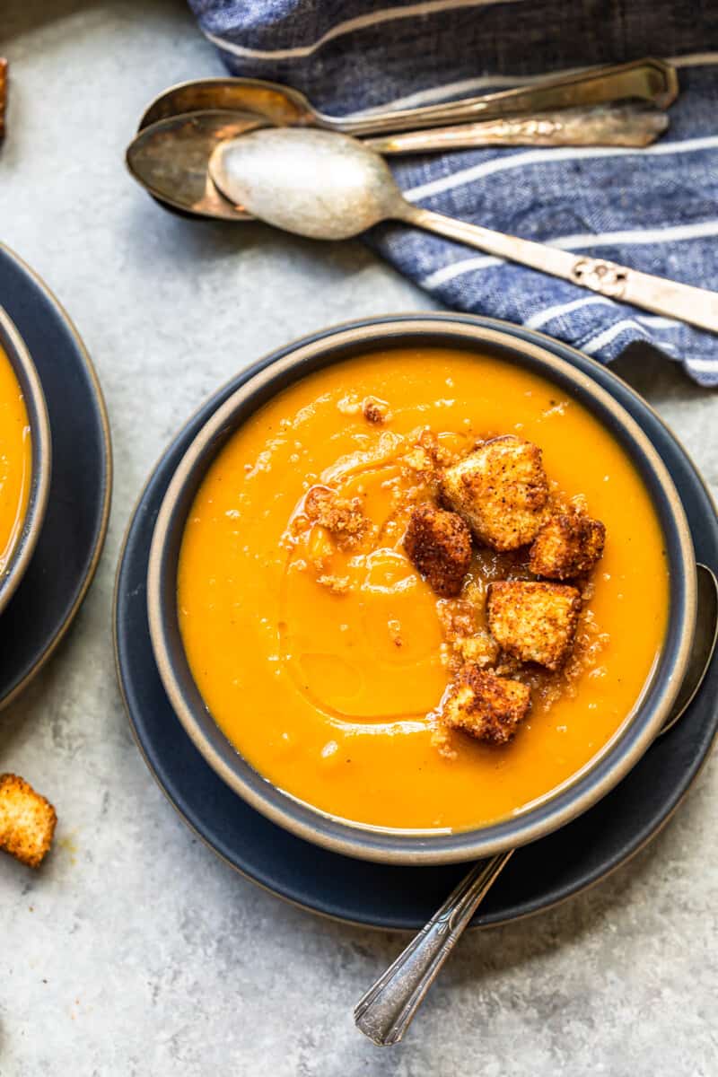 roasted butternut squash soup topped with cinnamon croutons in a black bowl