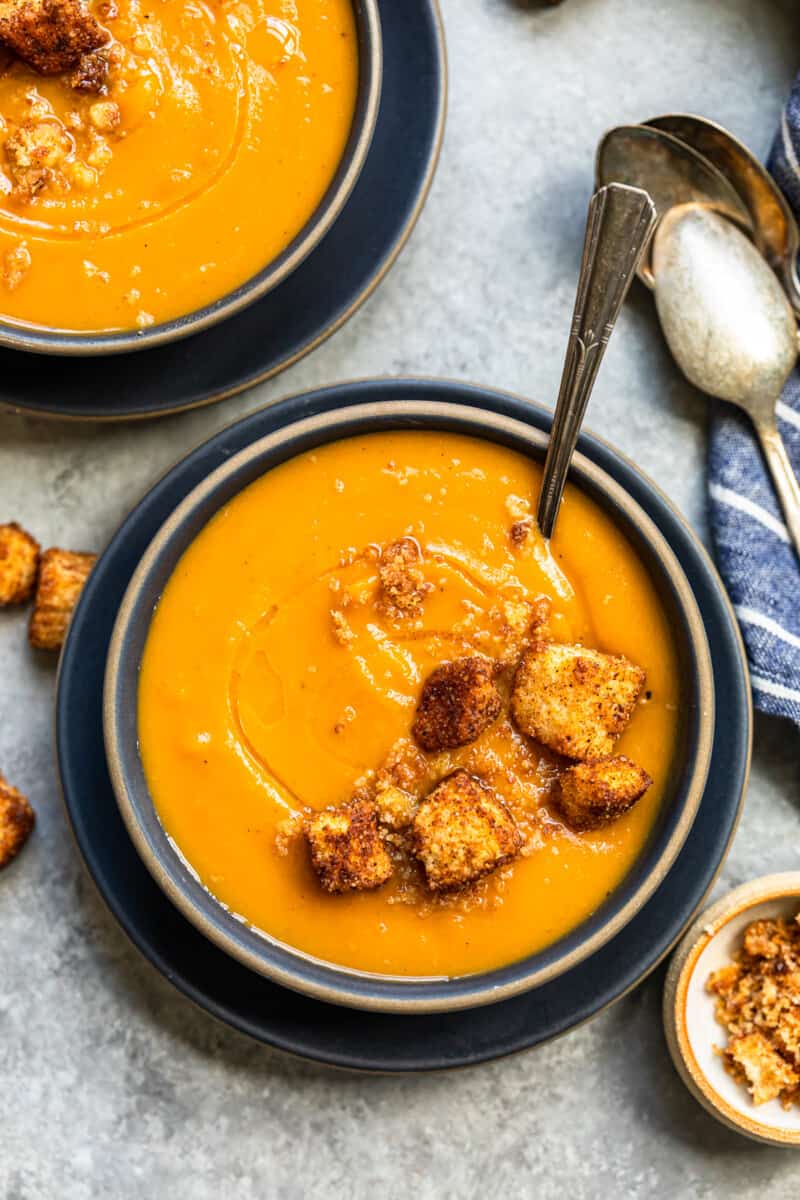 roasted butternut squash soup topped with cinnamon croutons in a black bowl with a spoon