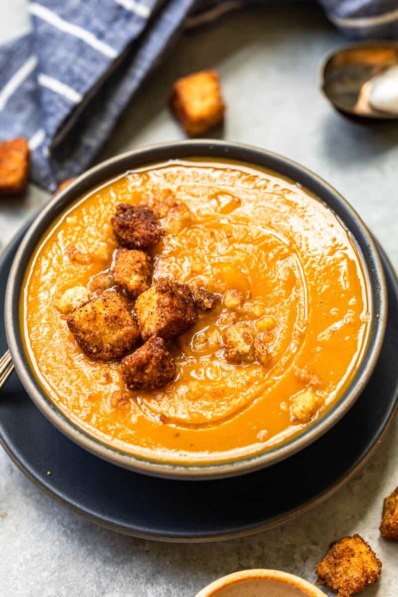 roasted butternut squash soup topped with cinnamon croutons in a black bowl