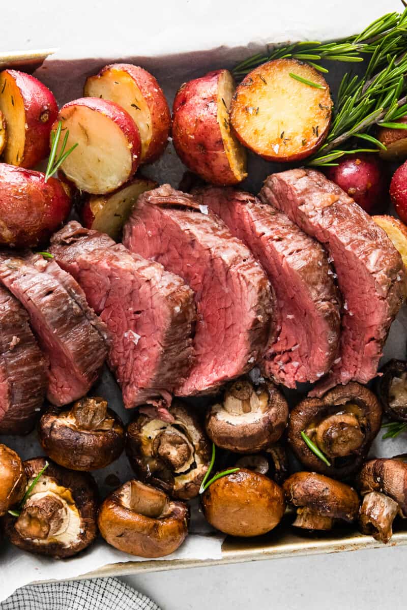 sheet pan with slices of beef and roasted red potatoes and mushrooms