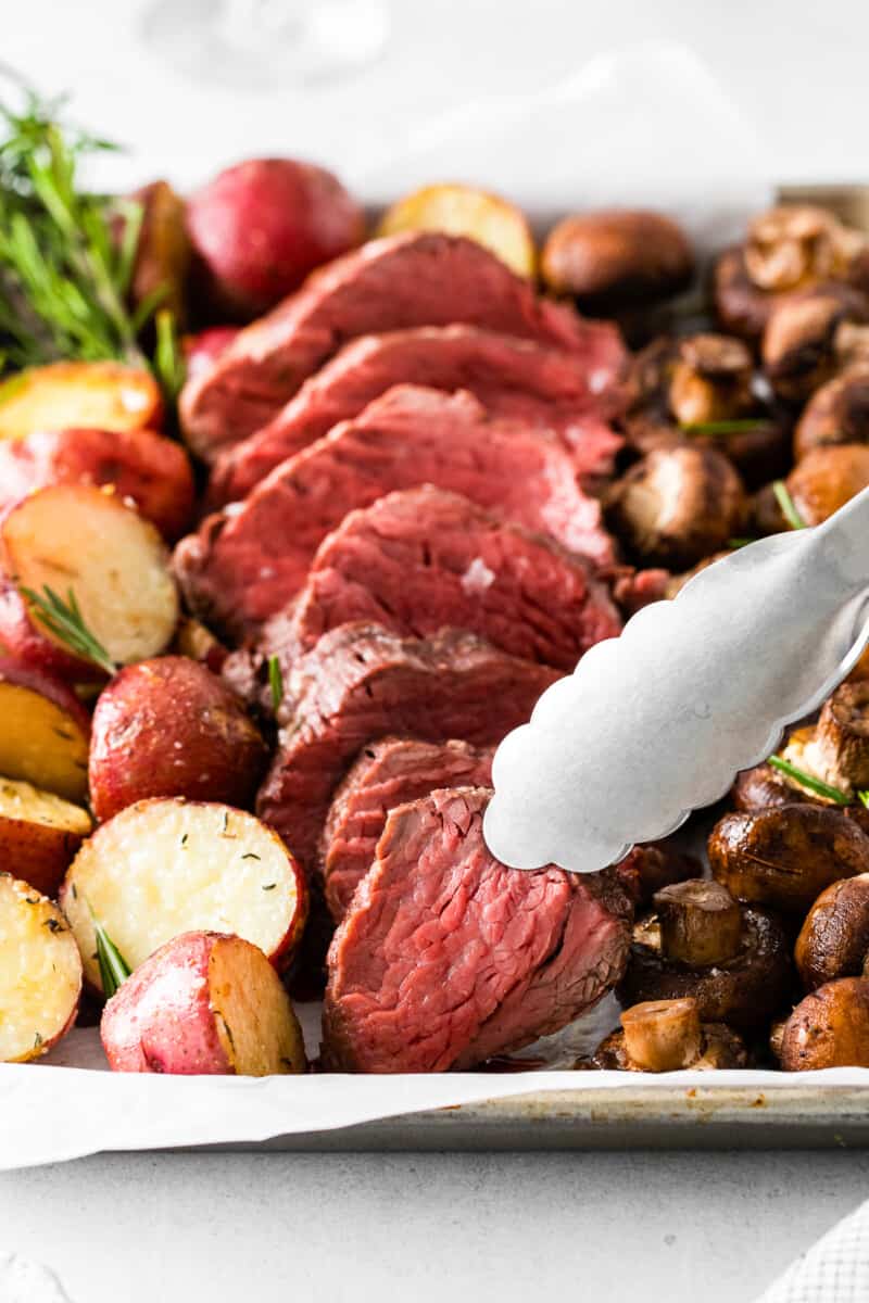 tongs grabbing a slice of beef.