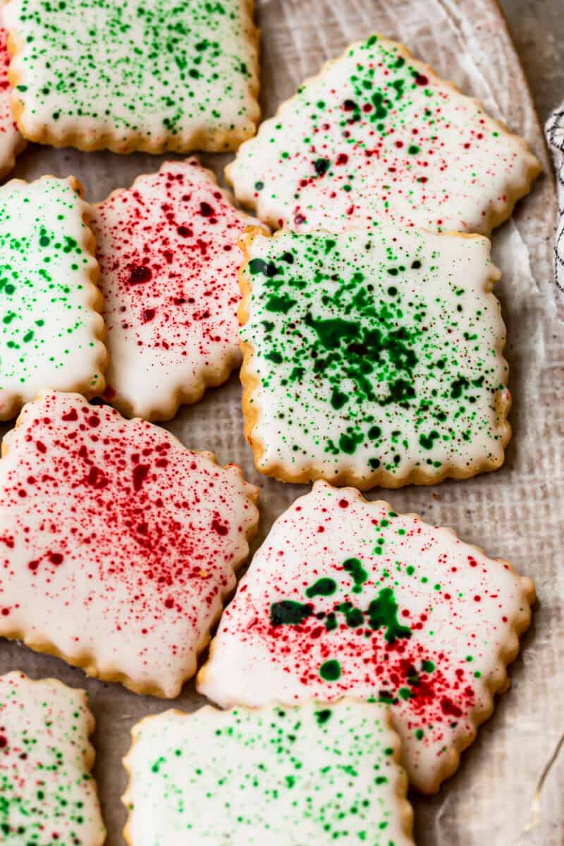 square sugar cookies topped with white icing and green and red splatter decoration