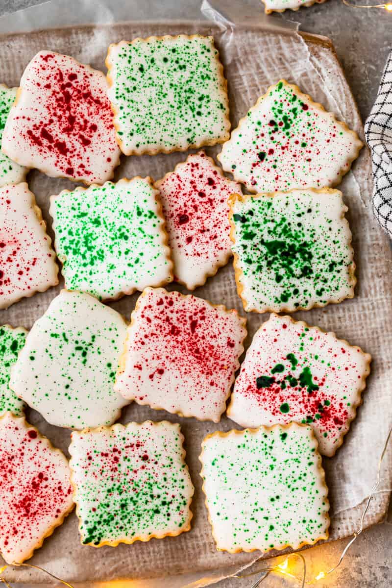 square sugar cookies topped with white icing and green and red splatter decoration