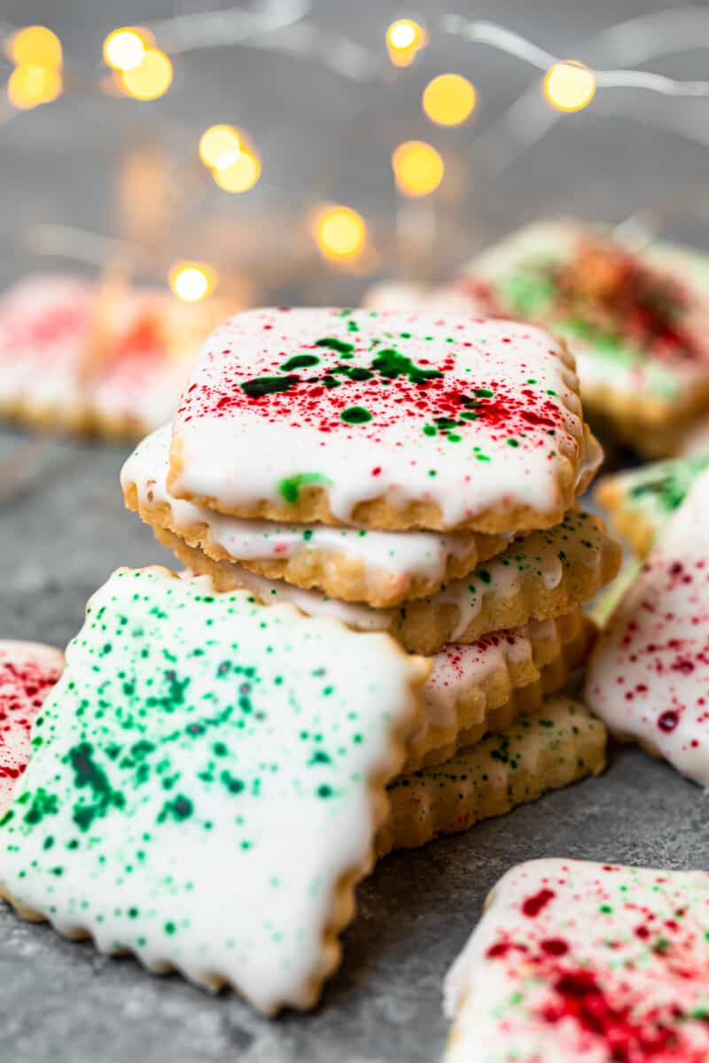 stack of square sugar cookies topped with white icing and green and red splatter decoration