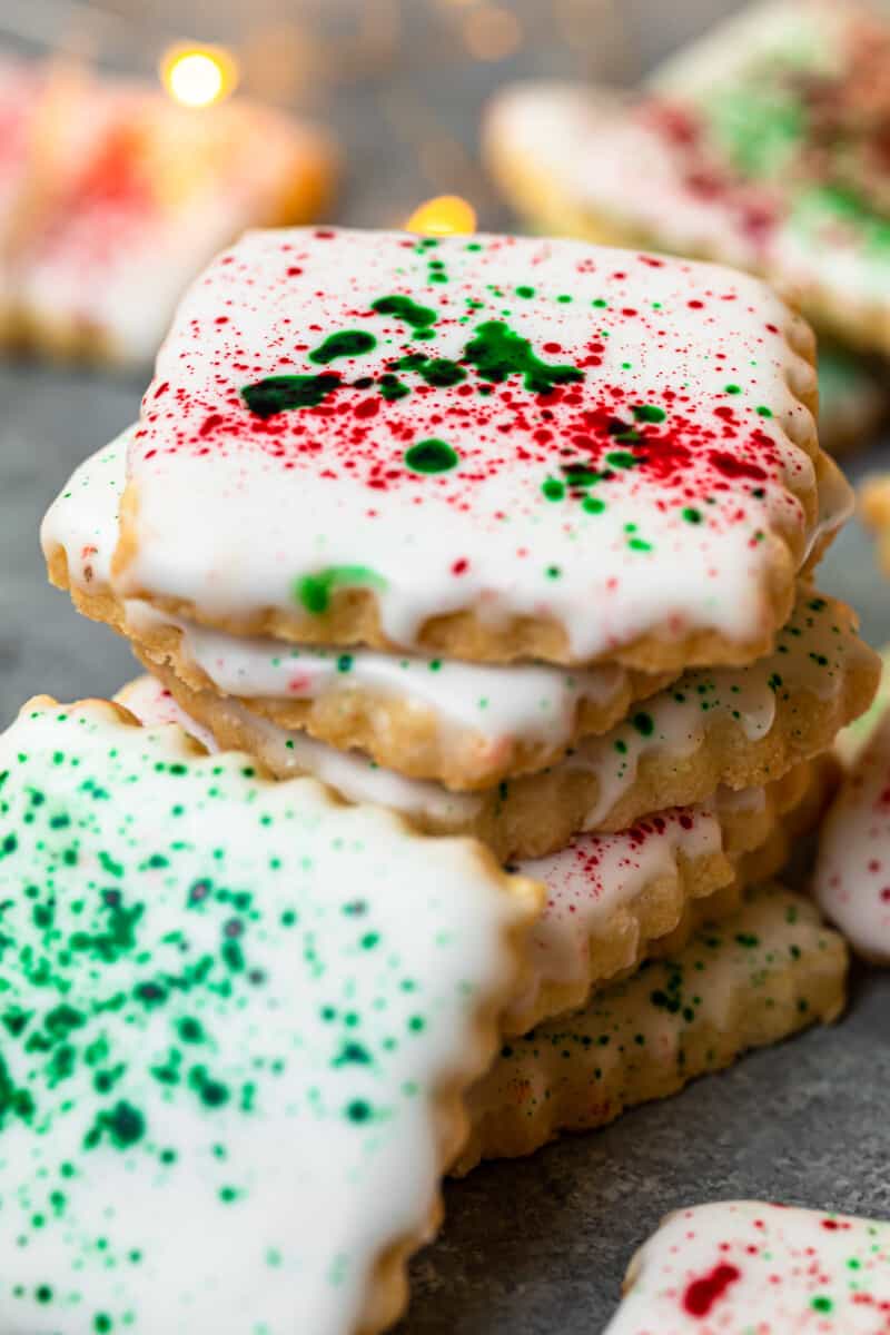 stack of square sugar cookies topped with white icing and green and red splatter decoration