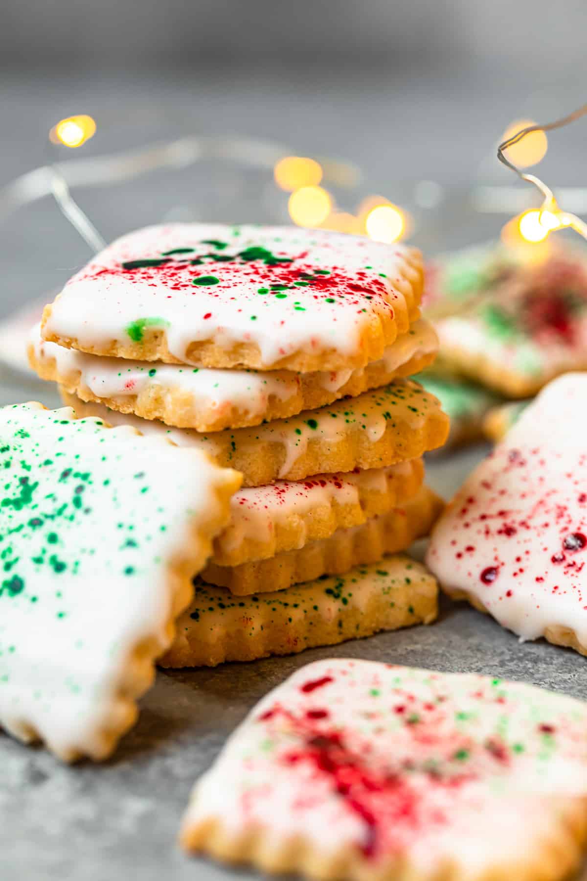 stack of square sugar cookies topped with white icing and green and red splatter decoration