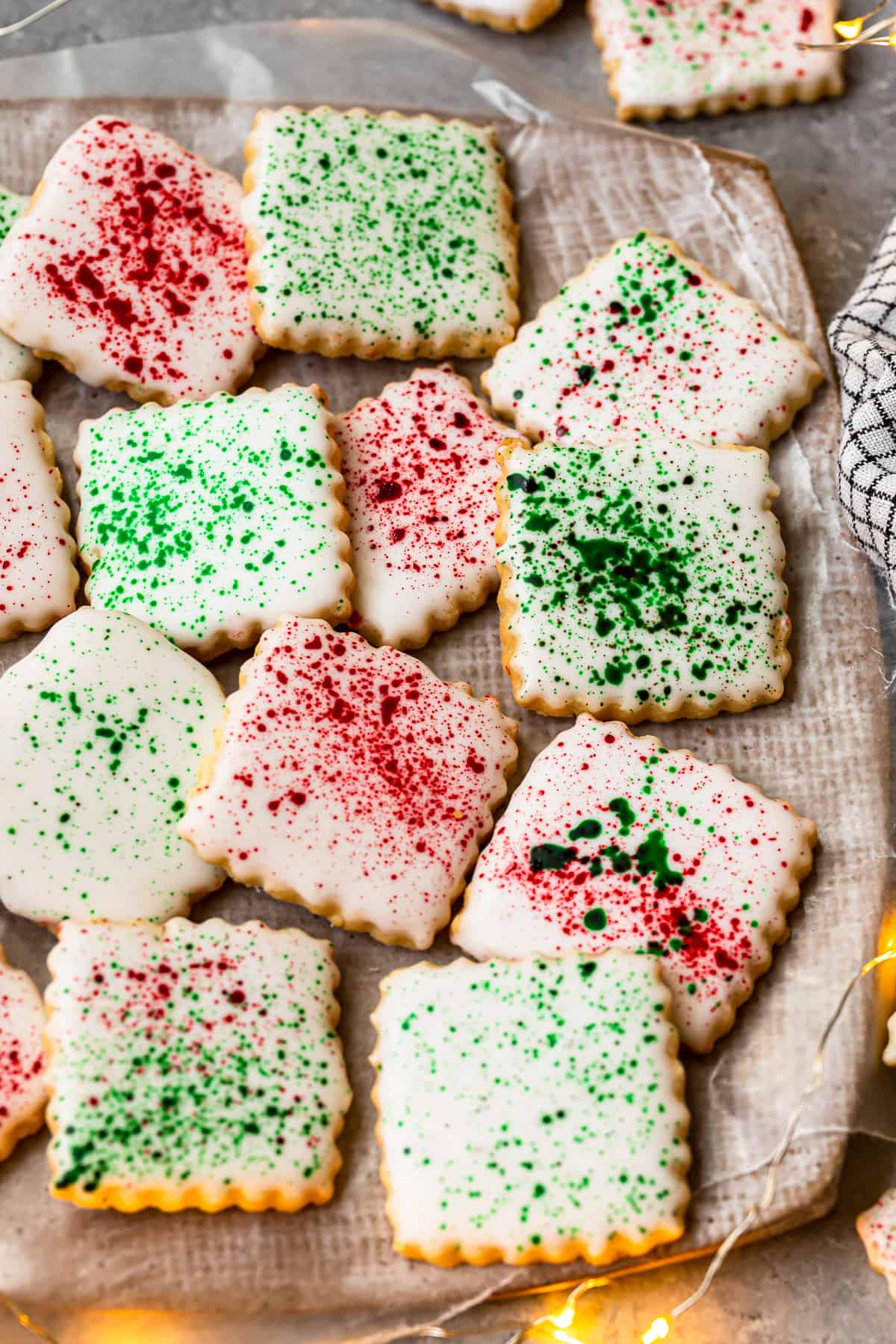 square sugar cookies topped with white icing and green and red splatter decoration