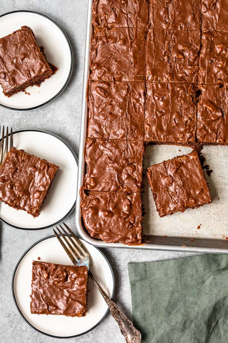 overhead image of pieces of texas sheet cake on white plates with forks