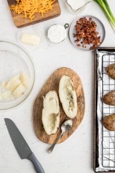 baked potato cut in half lengthwise with some of the potato scooped out