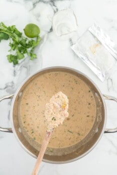 wooden spoon over a large pot filled with white chicken chili