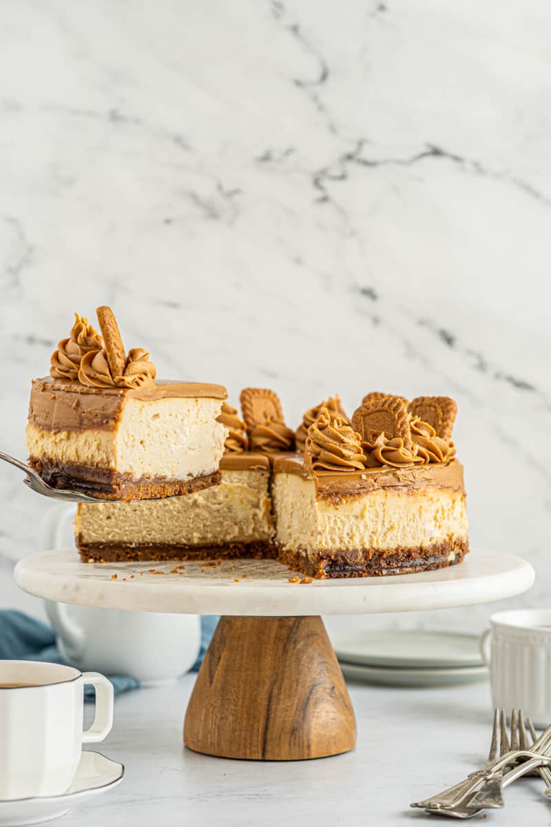 slice of biscoff cheesecake on a server being removed from the full cheesecake