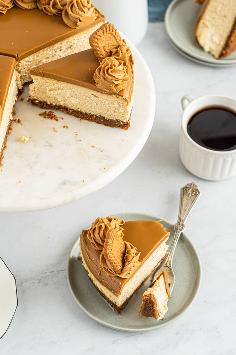slices of biscoff cheesecake on a cake stand and on a plate with a fork