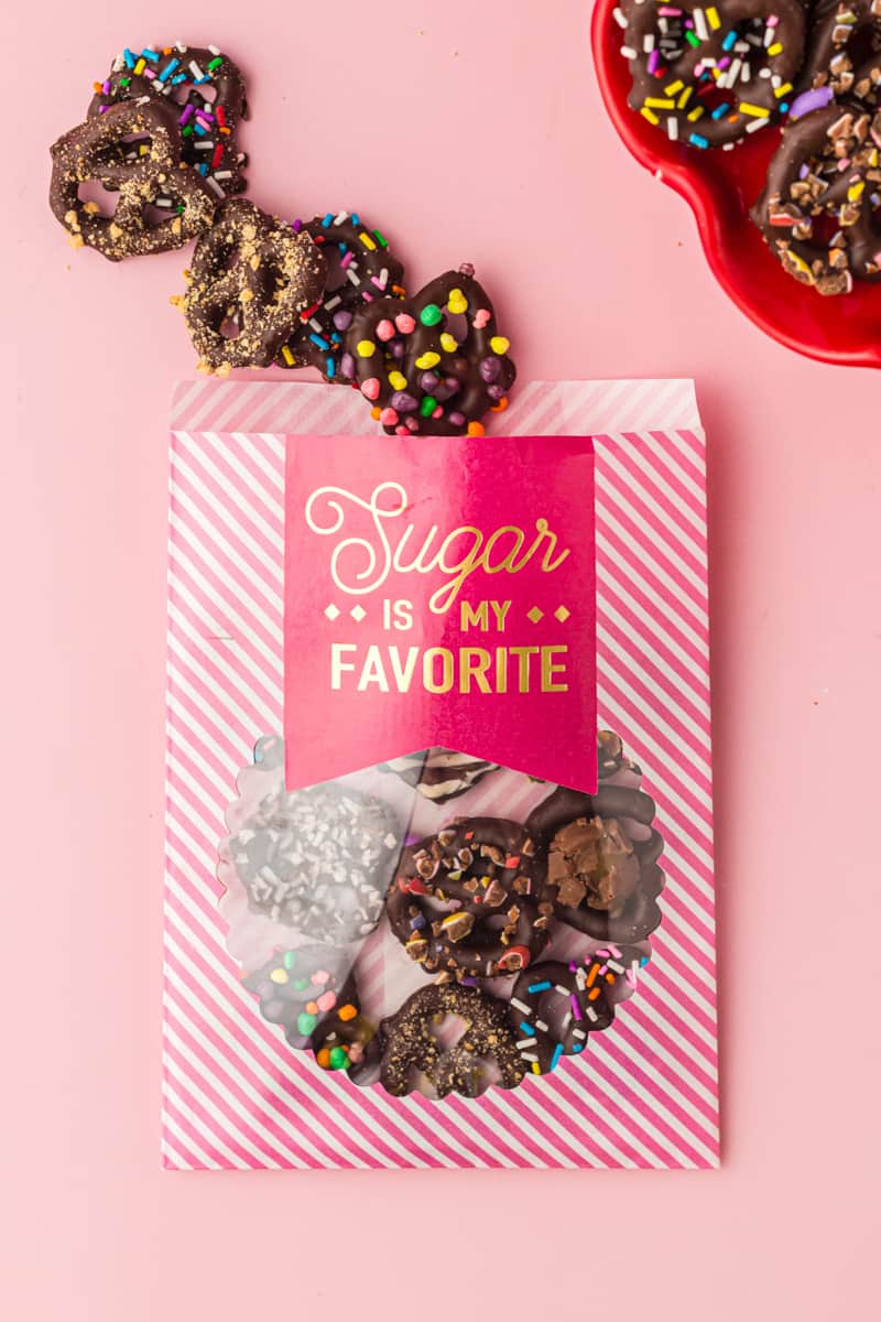 chocolate covered pretzels in a pink and white striped treat bag