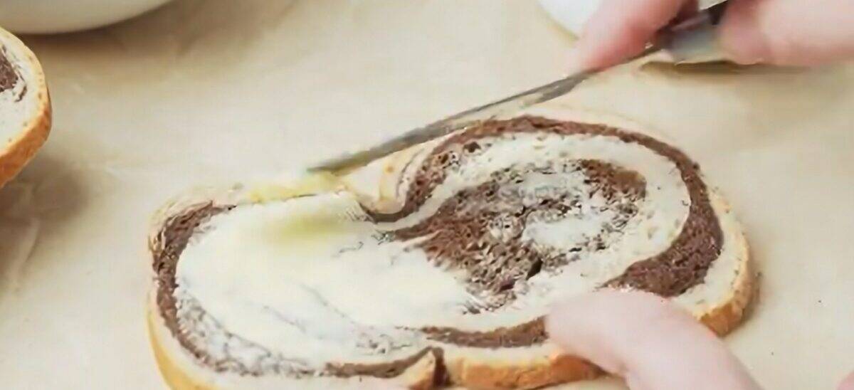 Buttering a slice of marbled rye bread with butter. 