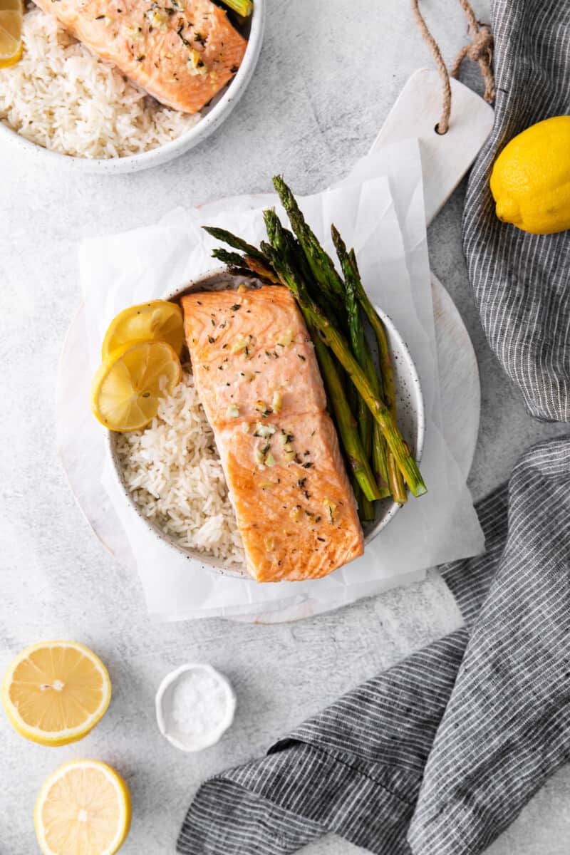 sheet pan lemon salmon on a bed of rice with asparagus in a white bowl.