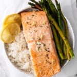 sheet pan lemon salmon on a bed of rice with asparagus in a white bowl.