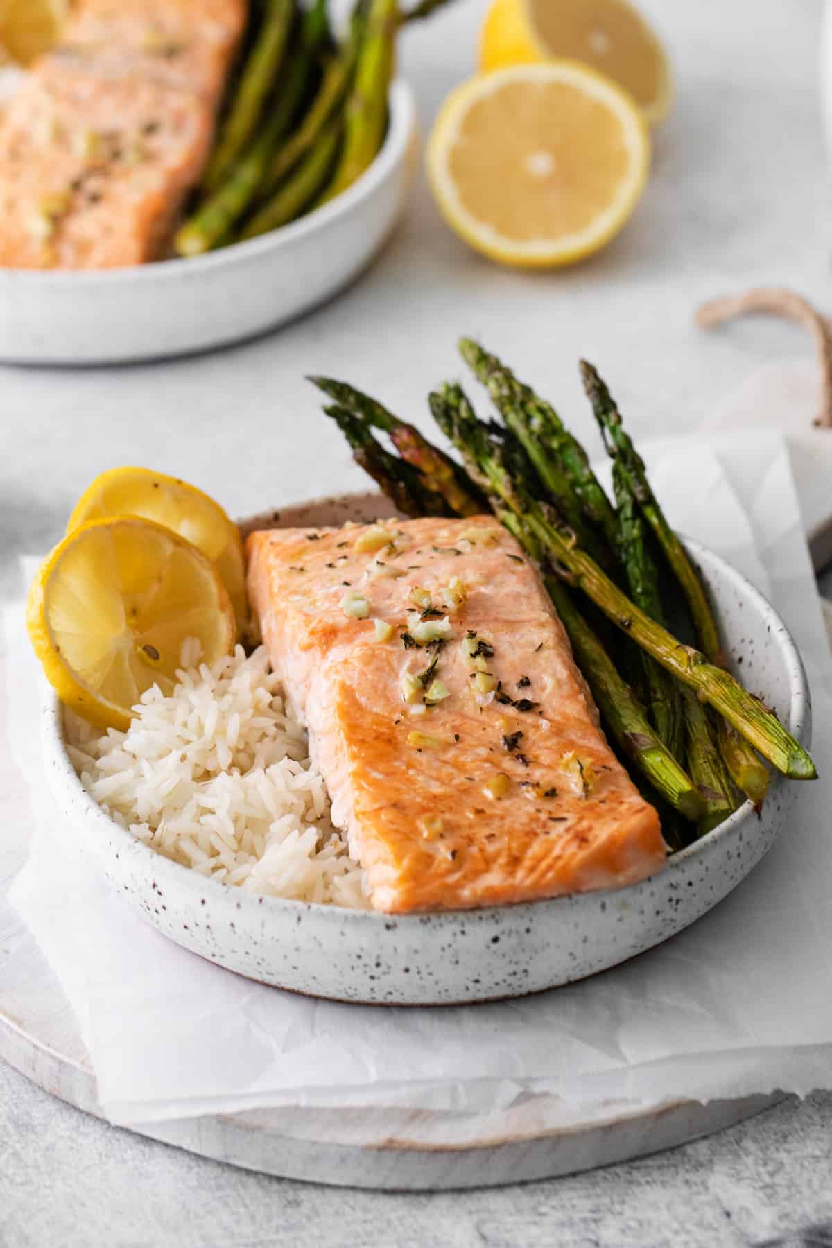 sheet pan lemon salmon on a bed of rice with asparagus in a white bowl.