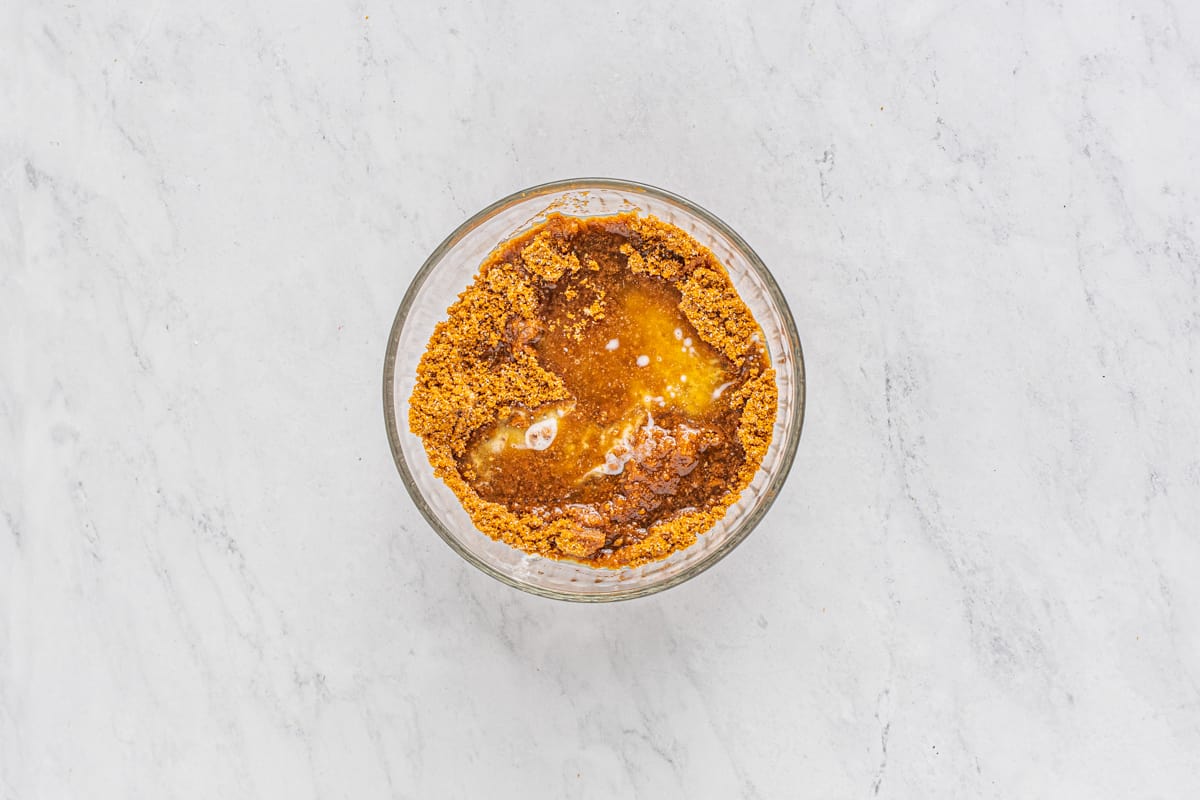 Biscoff cookie crumbs and melted butter in a glass bowl.