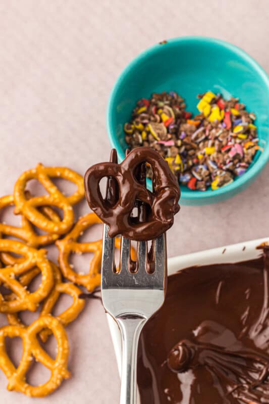 fork taking a chocolate dunked pretzel out of the melted chocolate