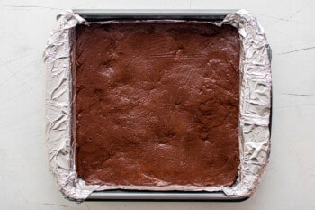 chocolate fudge in an aluminum foil lined square pan before chilling