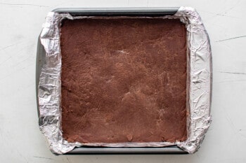 chocolate fudge in an aluminum foil lined square pan after chilling