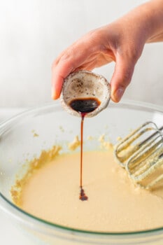 hand pouring vanilla into cornbread batter