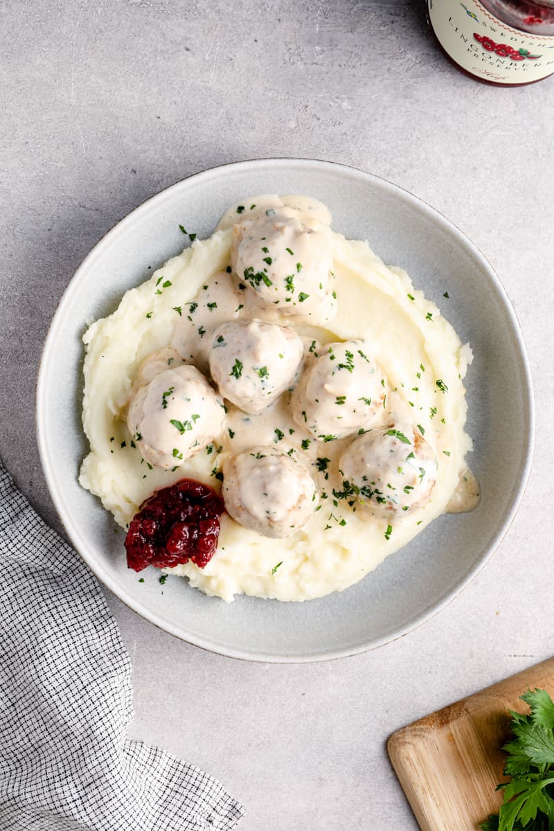 overhead image of crockpot swedish meatballs on top of mashed potatoes in a bowl