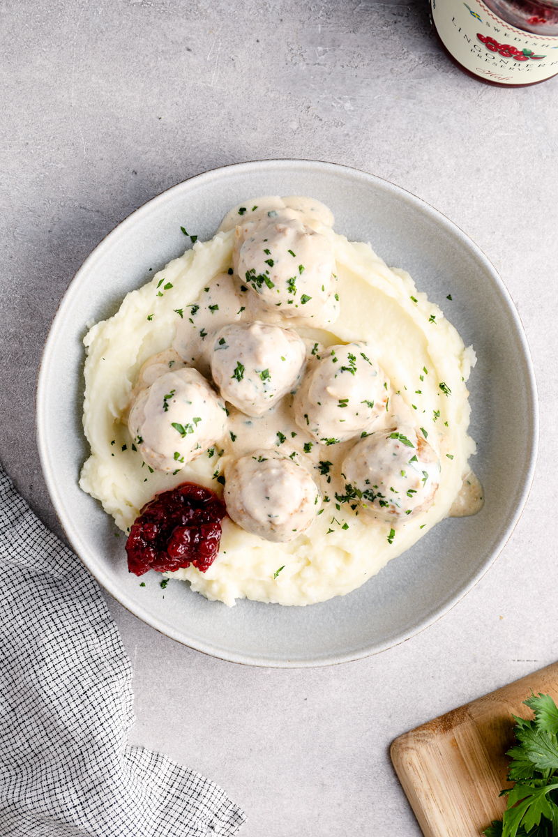 overhead image of crockpot swedish meatballs on top of mashed potatoes in a bowl
