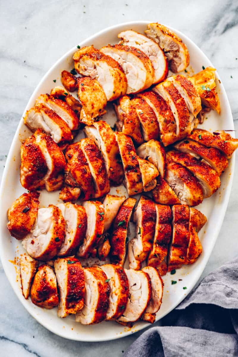 overhead image of sliced baked chicken thighs on a white serving tray