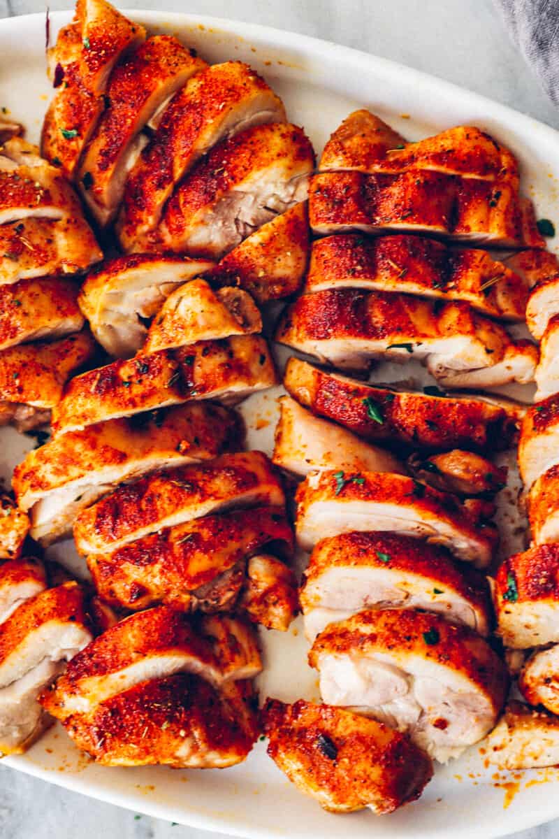 sliced baked chicken thighs on a white serving tray