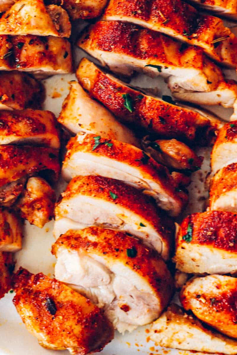 sliced baked chicken thighs on a white serving tray