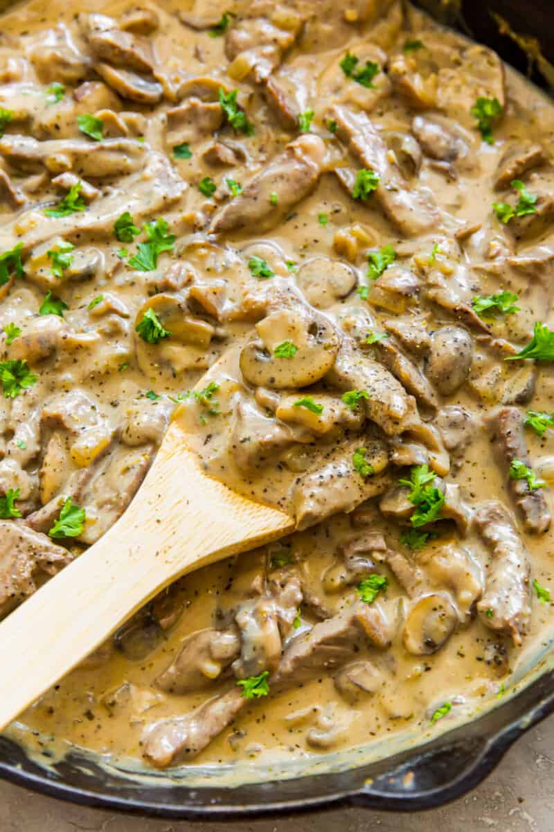beef stroganoff sauce in a skillet with a wood spoon