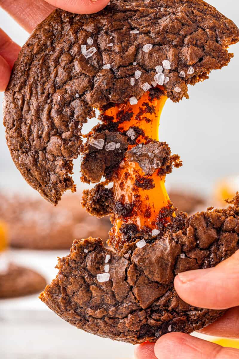 hands breaking a chocolate cookie in half showing the caramel center