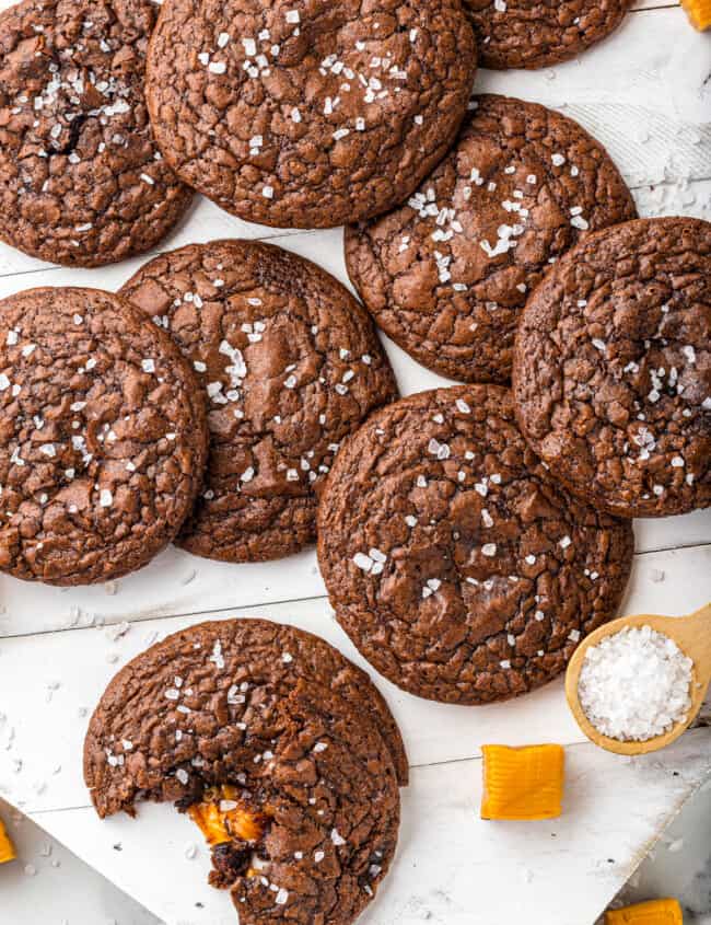 overhead image of chocolate cookies topped with sea salt with a bite taken from one cookie showing the caramel center