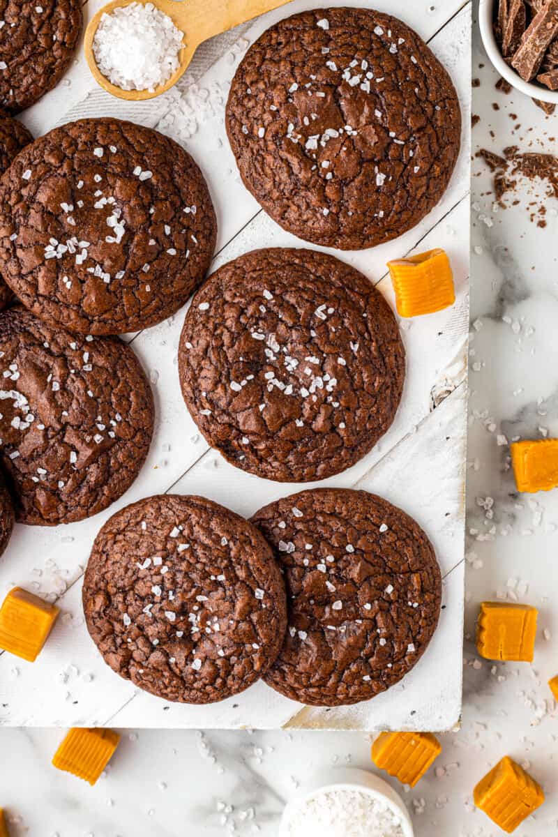 overhead image of chocolate cookies topped with sea salt on a white board