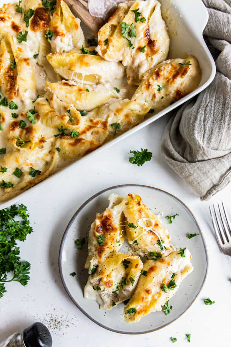 pasta shells stuffed with cheese and chicken topped with alfredo sauce on a white plate