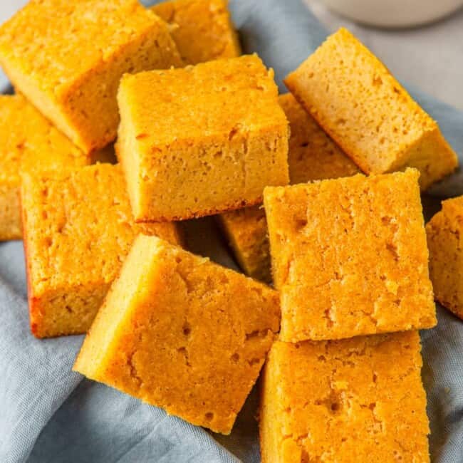 squares of cornbread in a basket lined with a blue napkin