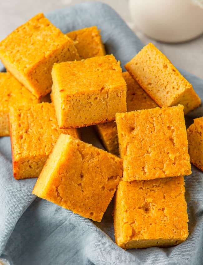 squares of cornbread in a basket lined with a blue napkin
