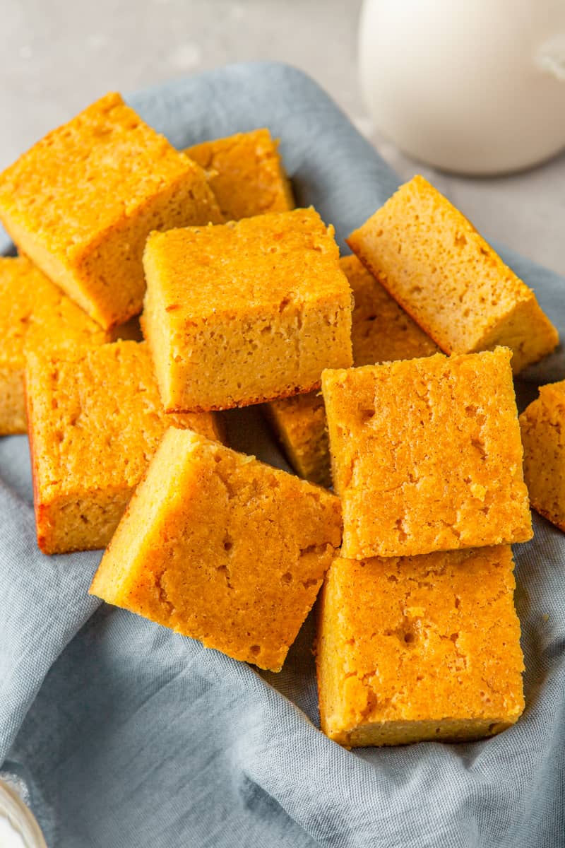 squares of cornbread in a basket lined with a blue napkin