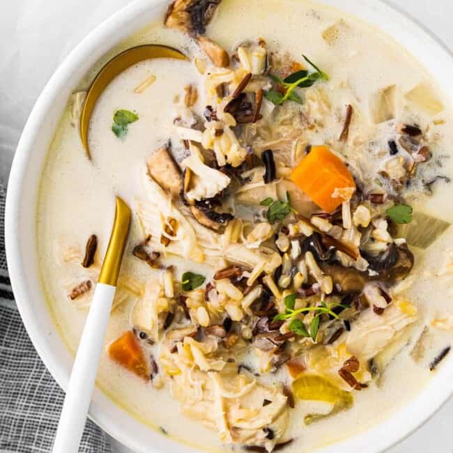 crockpot chicken wild rice soup in a white bowl with a spoon