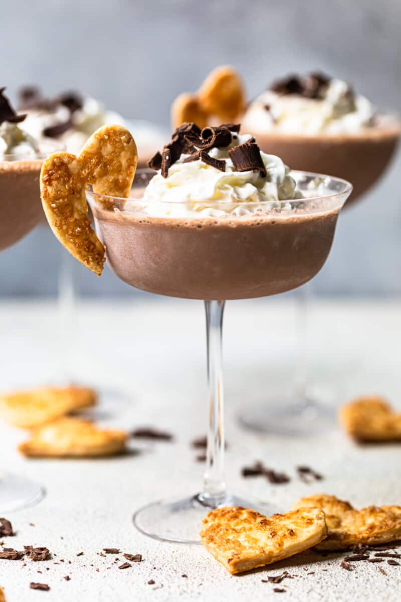 frozen french silk pie cocktails in glasses topped with whipped cream and chocolate shavings and garnished with baked pie crust cookies