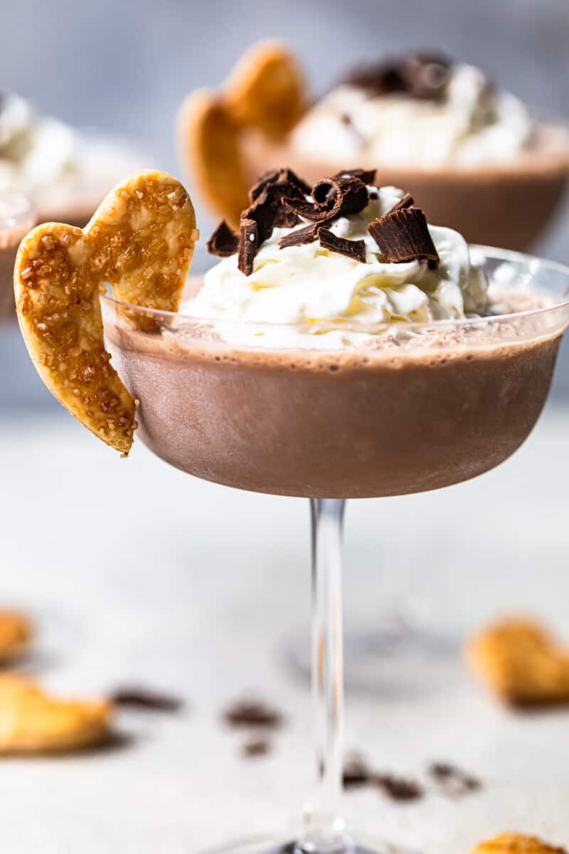 frozen french silk pie cocktail in a glass topped with whipped surf and chocolate shavings and garnished with baked pie husks cookie