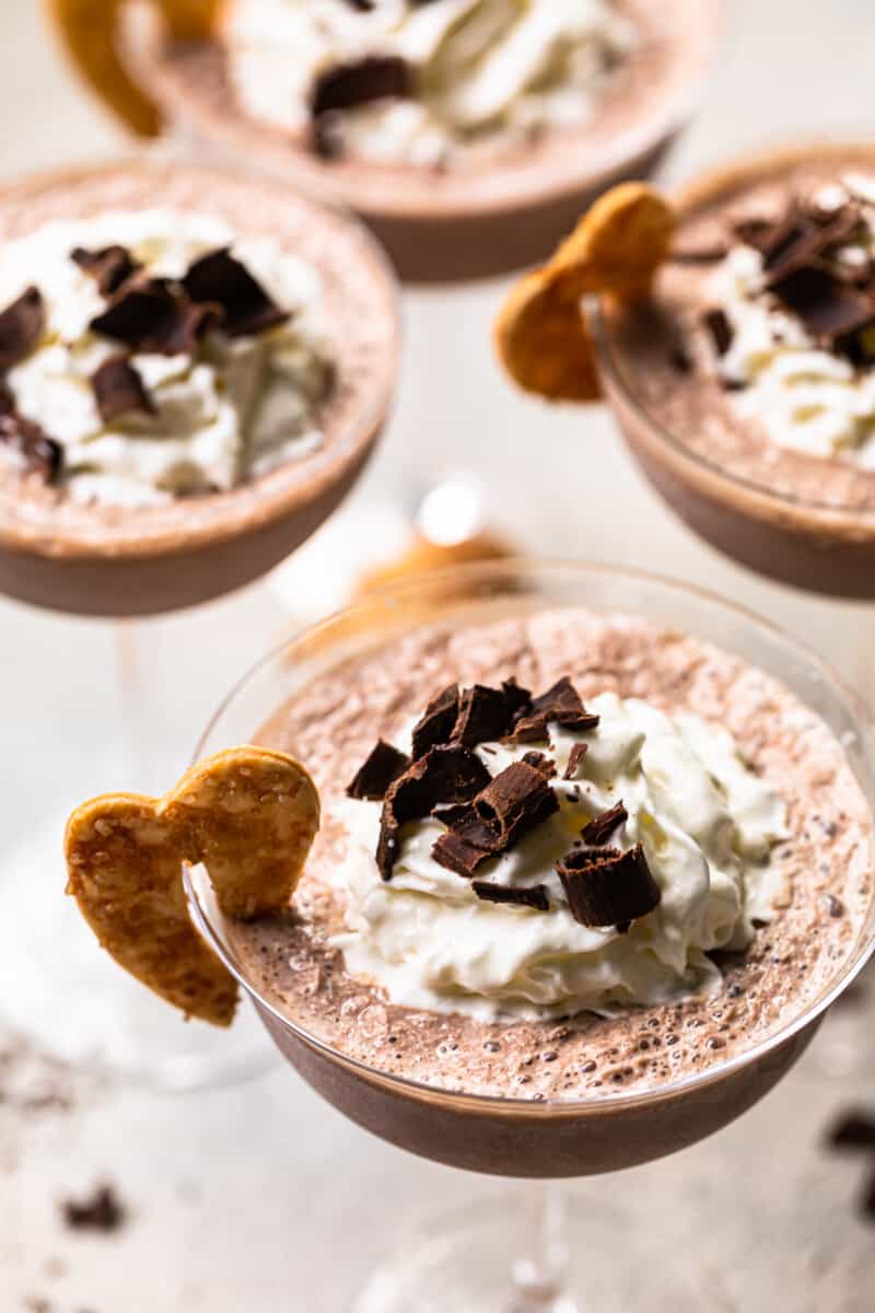 frozen french silk pie cocktails in glasses topped with whipped surf and chocolate shavings and garnished with baked pie husks cookies