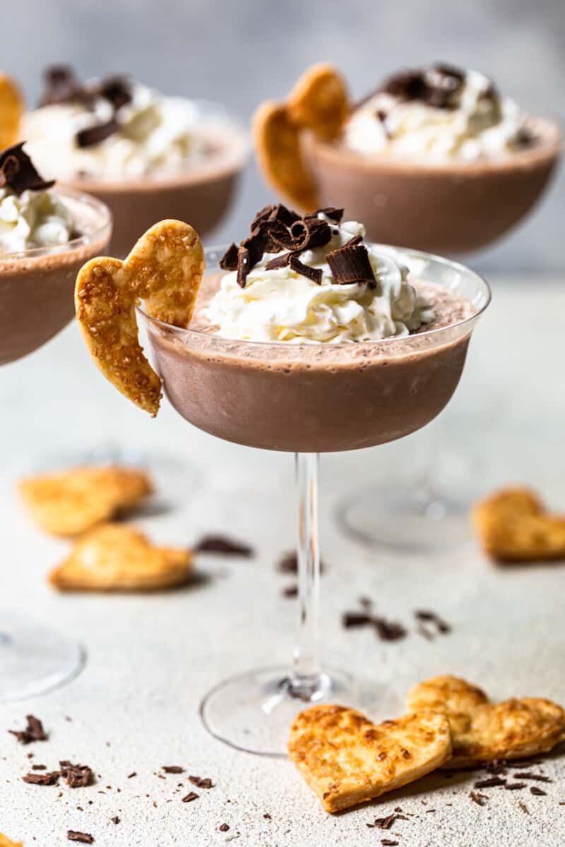 frozen french silk pie cocktails in glasses topped with whipped surf and chocolate shavings and garnished with baked pie husks cookies