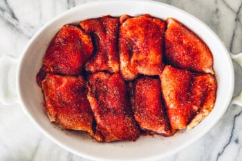 baked chicken thighs in a white baking dish before baking