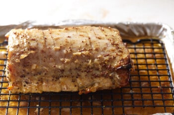 partially baked pork tenderloin on a wire rack set in a rimmed baking sheet.