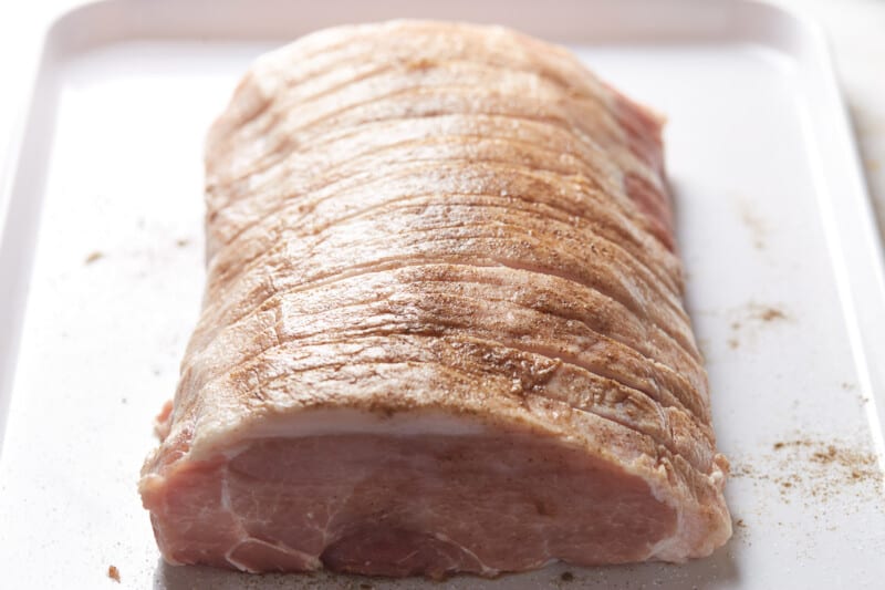 scored raw pork tenderloin on a baking sheet.