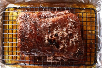 glaze poured over baked pork tenderloin on a wire rack set in a rimmed baking sheet.